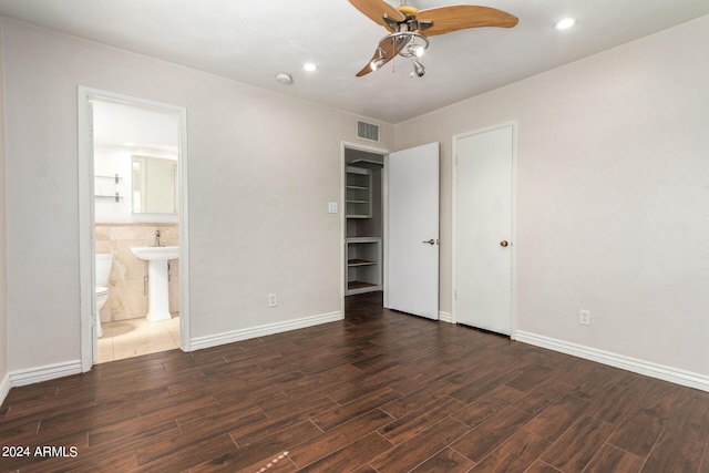 unfurnished bedroom with ensuite bath, dark wood-type flooring, sink, and ceiling fan