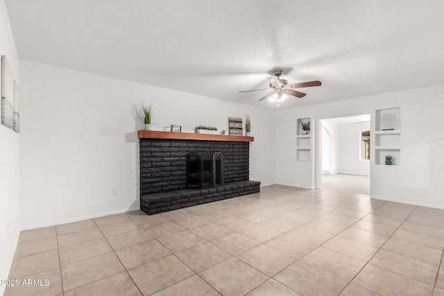 living area featuring built in shelves, light tile patterned flooring, a ceiling fan, baseboards, and a brick fireplace