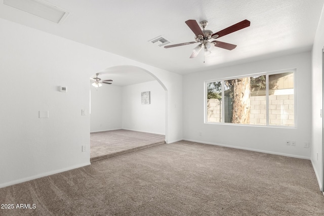 spare room featuring arched walkways, ceiling fan, carpet flooring, visible vents, and baseboards