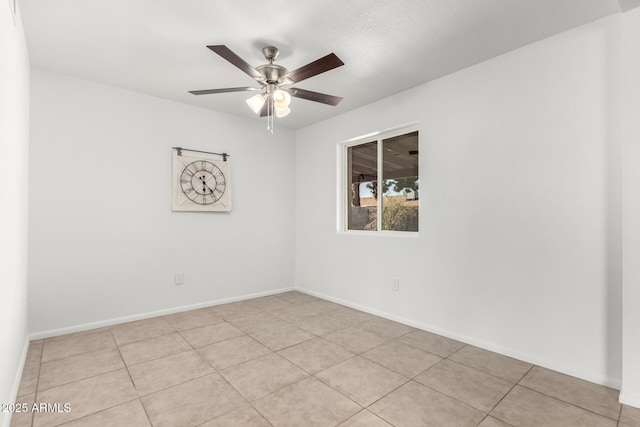 spare room with a ceiling fan and baseboards