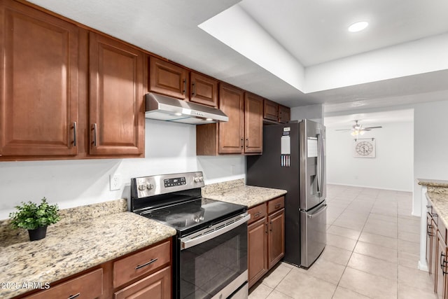 kitchen featuring light tile patterned floors, under cabinet range hood, a ceiling fan, appliances with stainless steel finishes, and light stone countertops