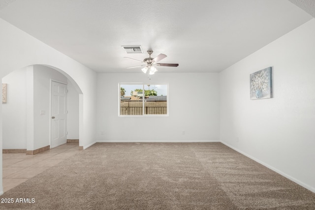 unfurnished room with baseboards, visible vents, arched walkways, a ceiling fan, and light colored carpet