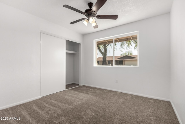 unfurnished bedroom with carpet floors, ceiling fan, baseboards, and a closet