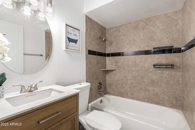 bathroom with toilet, vanity, shower / washtub combination, and a textured wall