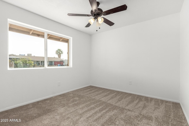 carpeted spare room featuring ceiling fan and baseboards