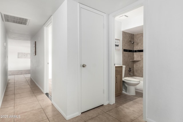 corridor with light tile patterned floors, baseboards, and visible vents