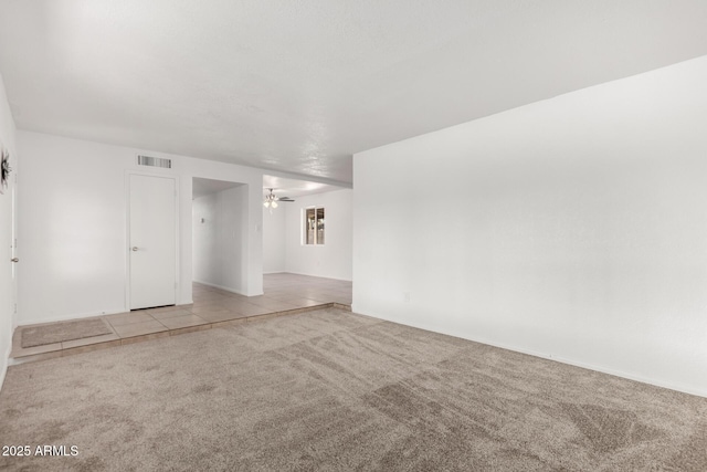 carpeted empty room with visible vents and tile patterned floors