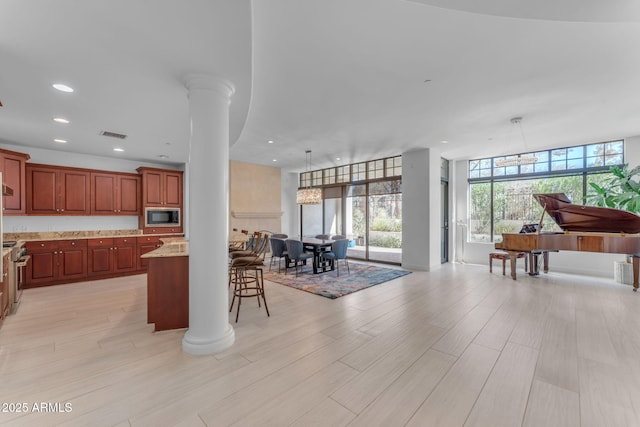 kitchen with built in microwave, light stone countertops, pendant lighting, and ornate columns