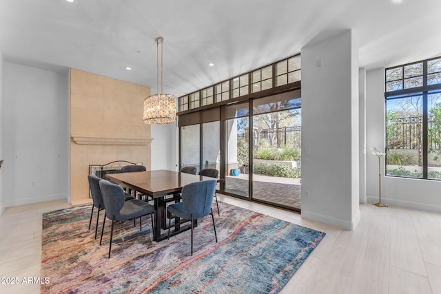 dining room featuring a chandelier, a tile fireplace, and light wood-type flooring