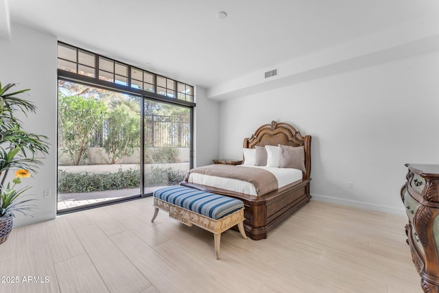 bedroom featuring light hardwood / wood-style flooring, access to outside, and a wall of windows