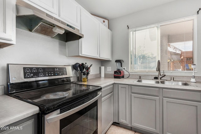 kitchen with stainless steel electric stove, light countertops, gray cabinetry, a sink, and under cabinet range hood