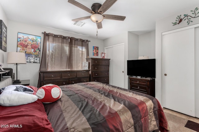 bedroom with ceiling fan, visible vents, and multiple closets