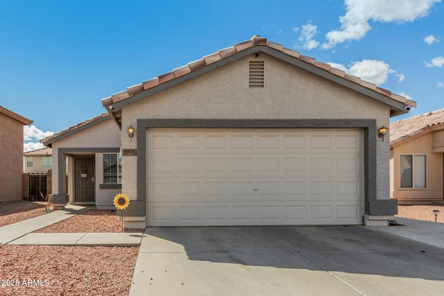 ranch-style house featuring concrete driveway, a tile roof, an attached garage, and stucco siding