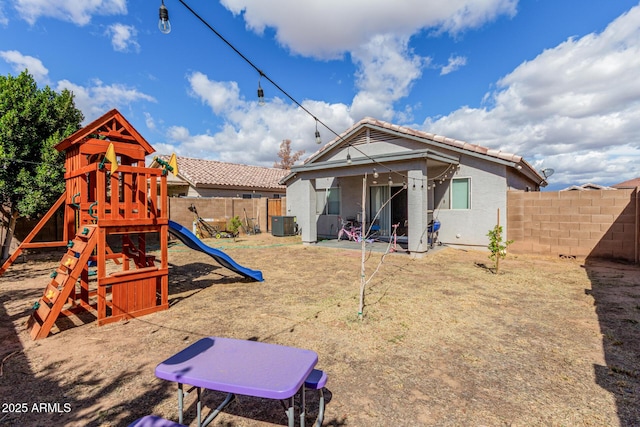 exterior space featuring central AC, a playground, a fenced backyard, and a tile roof