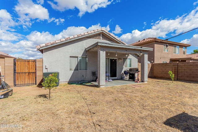 back of house featuring a patio, a tile roof, a fenced backyard, a gate, and stucco siding