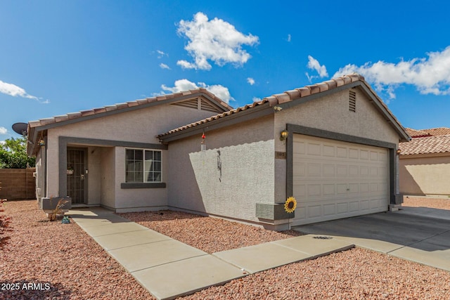 view of front facade featuring an attached garage, a tiled roof, concrete driveway, and stucco siding