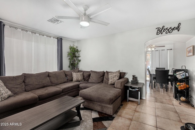 living area with a ceiling fan, arched walkways, visible vents, and light tile patterned floors