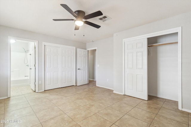 unfurnished bedroom with ceiling fan, light tile patterned floors, ensuite bath, and multiple closets