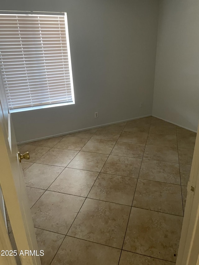 unfurnished room with baseboards and light tile patterned floors