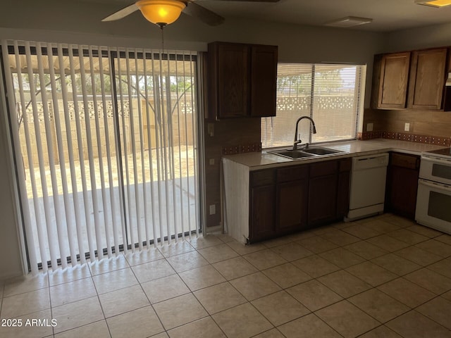 kitchen featuring white appliances, light tile patterned floors, a sink, light countertops, and backsplash