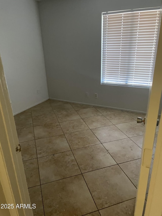 spare room with light tile patterned floors and baseboards