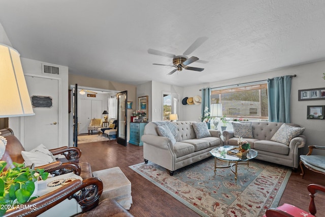 living room featuring ceiling fan, dark hardwood / wood-style floors, and a textured ceiling