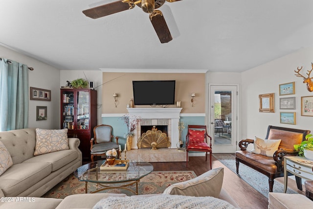 living room with ceiling fan, wood-type flooring, and a tiled fireplace