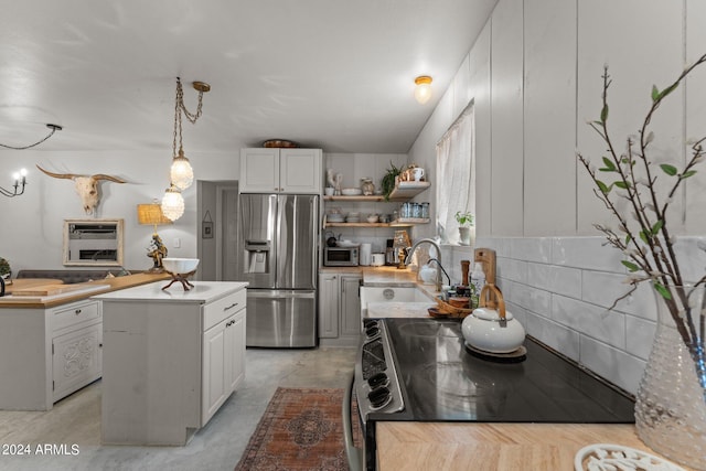 kitchen featuring pendant lighting, sink, appliances with stainless steel finishes, white cabinetry, and a kitchen island