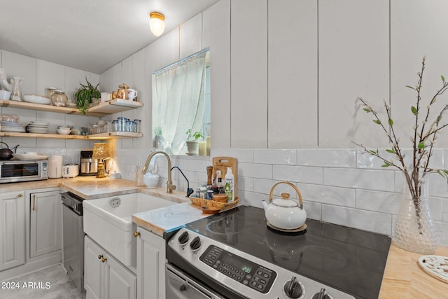 kitchen featuring appliances with stainless steel finishes, sink, decorative backsplash, and white cabinets