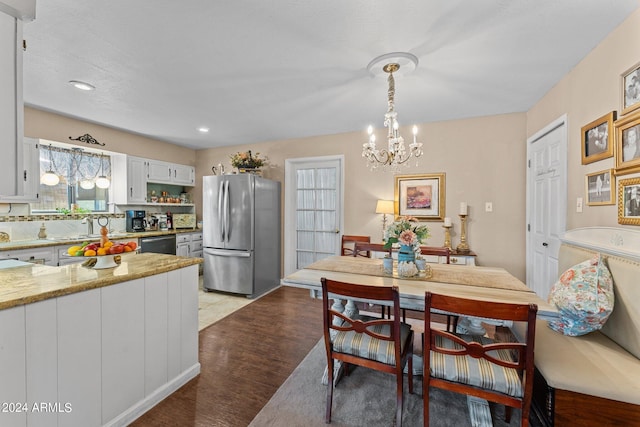 dining area featuring sink, light hardwood / wood-style floors, and a chandelier