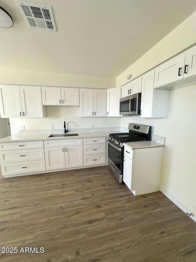 kitchen featuring dark wood-type flooring, sink, white cabinetry, a textured ceiling, and appliances with stainless steel finishes