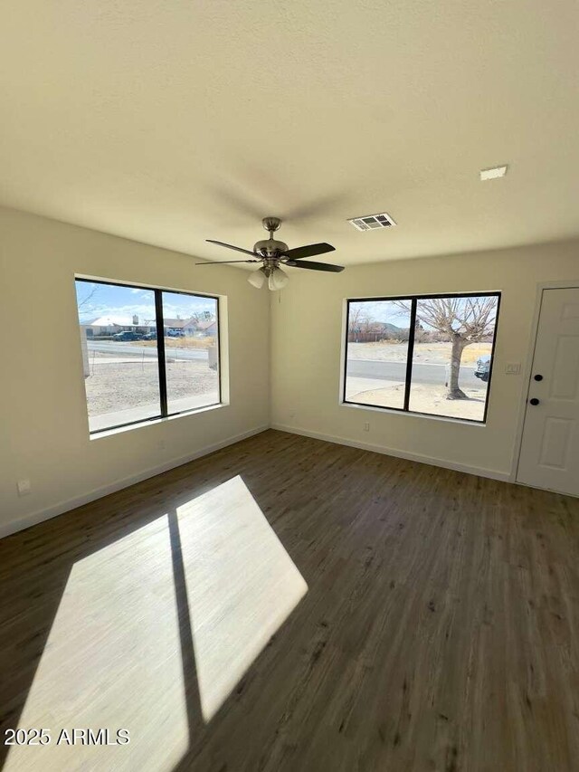 empty room with ceiling fan and dark hardwood / wood-style floors