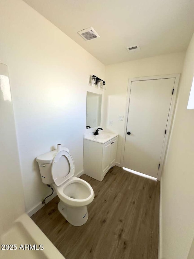 bathroom with hardwood / wood-style flooring, vanity, and toilet