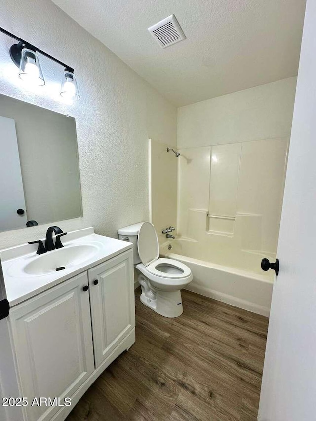 full bathroom with toilet, bathtub / shower combination, a textured ceiling, vanity, and hardwood / wood-style flooring