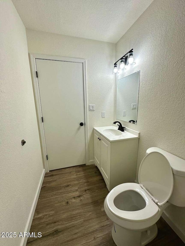 bathroom featuring hardwood / wood-style flooring, vanity, a textured ceiling, and toilet