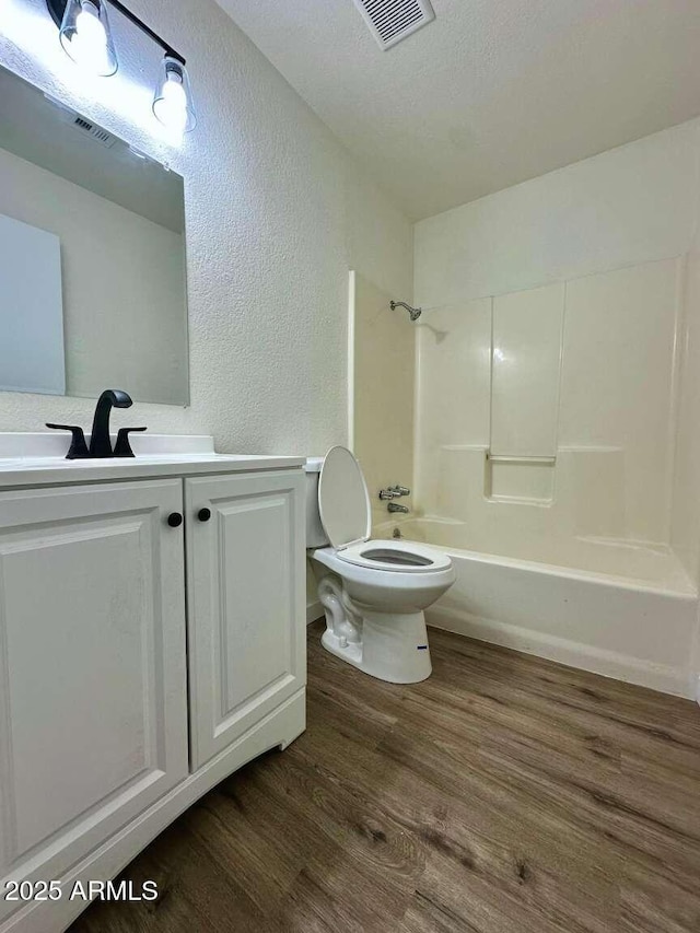 full bathroom featuring toilet, bathing tub / shower combination, a textured ceiling, vanity, and hardwood / wood-style floors