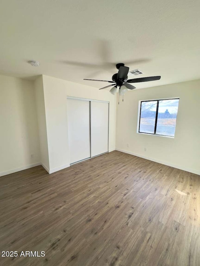 unfurnished bedroom featuring dark hardwood / wood-style floors, ceiling fan, and a closet