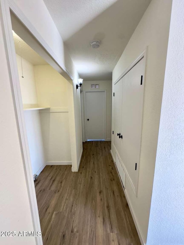 hall with wood-type flooring and a textured ceiling