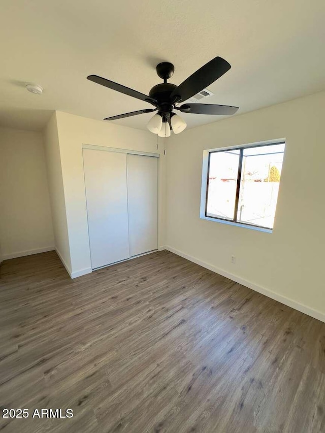 unfurnished bedroom featuring ceiling fan, wood-type flooring, and a closet