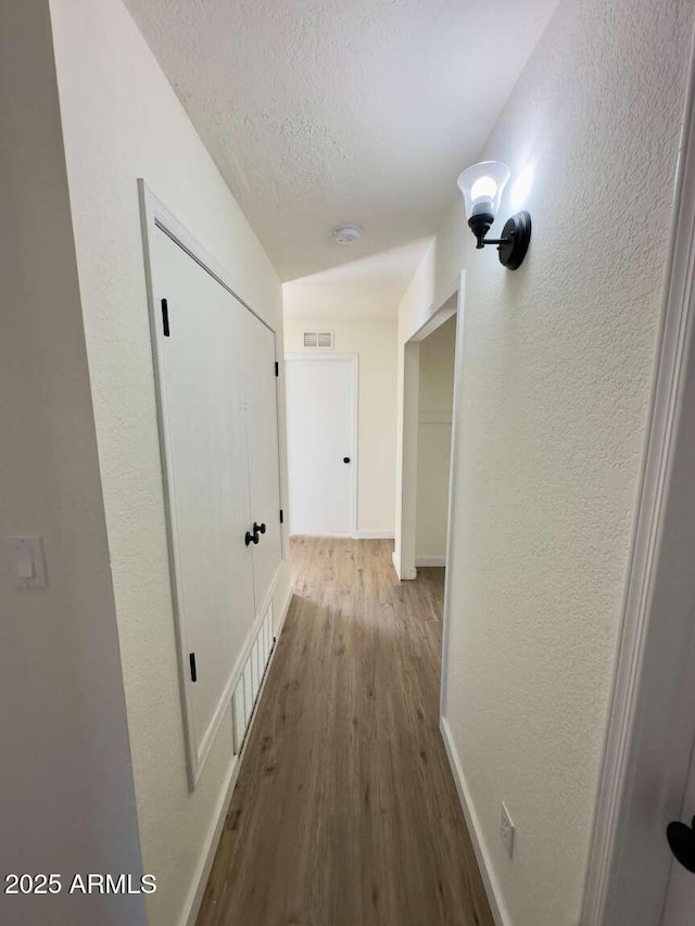 hallway featuring wood-type flooring and a textured ceiling