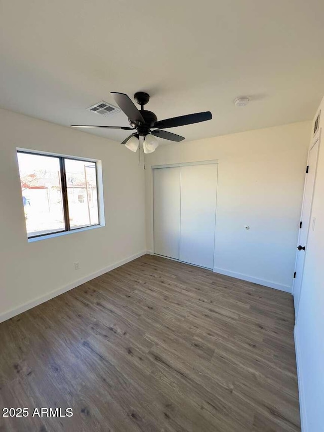 unfurnished bedroom with dark wood-type flooring, ceiling fan, and a closet