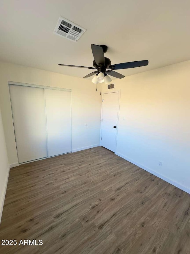 unfurnished bedroom with dark hardwood / wood-style floors, ceiling fan, and a closet