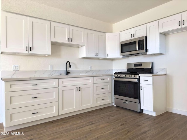 kitchen featuring dark wood-type flooring, sink, stainless steel appliances, light stone countertops, and white cabinets