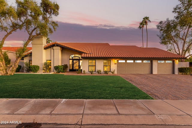 mediterranean / spanish home featuring a garage and a yard