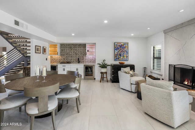 tiled dining space with indoor bar, wine cooler, and a high end fireplace