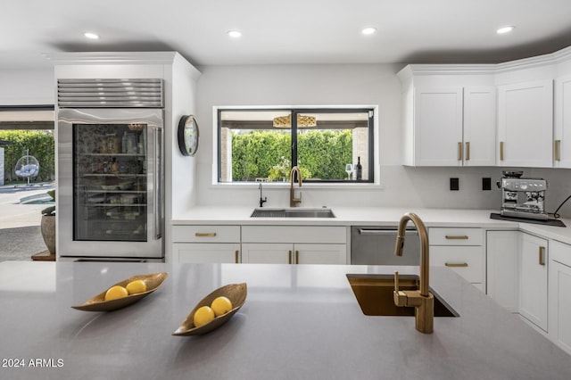 kitchen featuring wine cooler, sink, dishwasher, and white cabinets