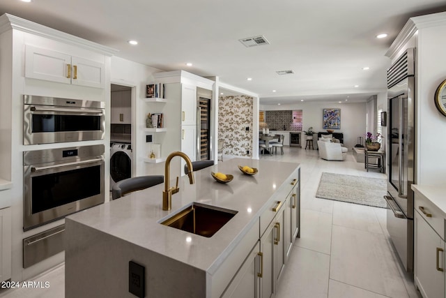 kitchen with appliances with stainless steel finishes, white cabinetry, sink, wine cooler, and a large island