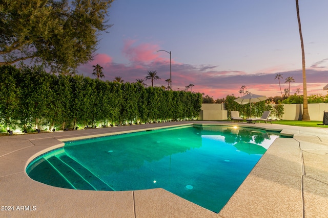 pool at dusk featuring a patio