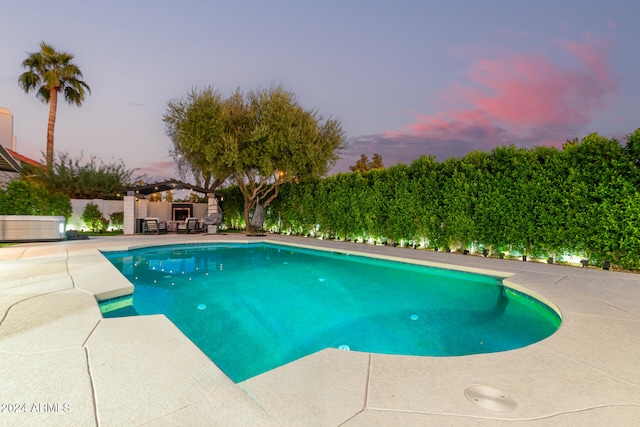 pool at dusk with a patio area