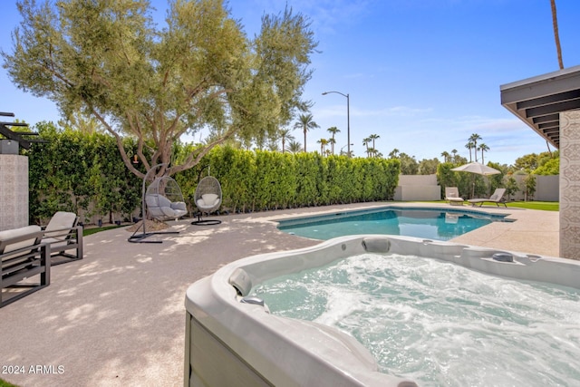 view of swimming pool featuring a hot tub and a patio area